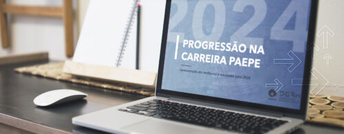 Notebook em cima de uma mesa de trabalho com o vídeo da Progressão 2024 sendo exibido