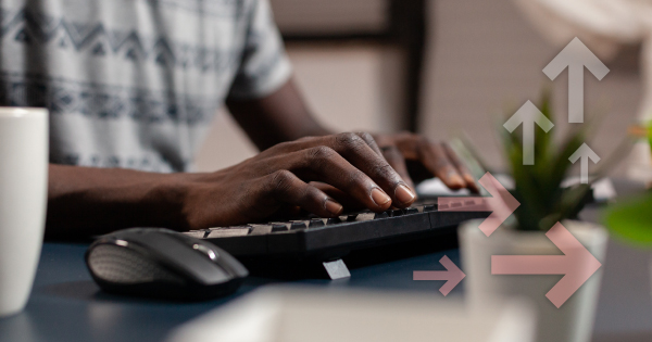 mãos de uma pessoa digitando no teclado de um computador numa mesa de escritório