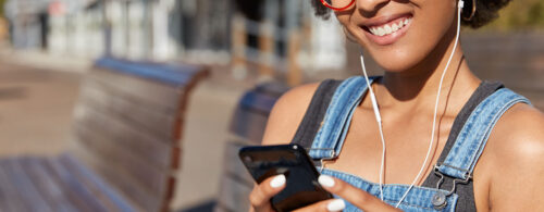 Mulher negra sorrindo e utilizando o celular