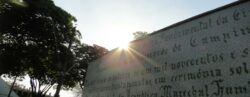 Destaque para o sol parcialmente coberto pelo muro com imagem de Zeferino Vaz na Praça das Bandeiras