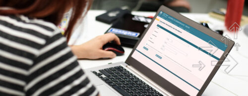 Mulher acessando o sistema Gestão de Desempenho com um notebook em ambiente de trabalho