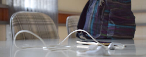 Celular, fone de ouvido e mochila sobre uma mesa de reunião
