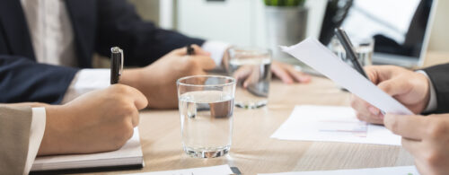 Close up das mãos de empresários segurando papelada na mesa de conferência da reunião.