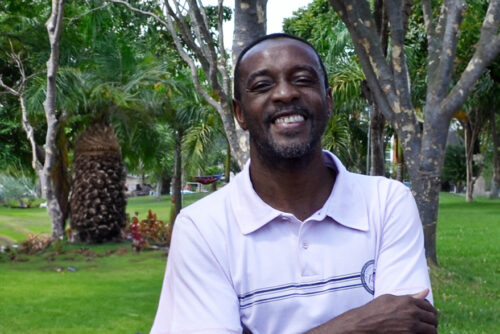 Servidor Amaral sorrindo, de braços cruzados, com a Praça da Paz ao fundo