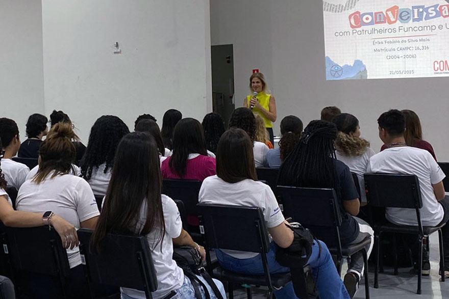 Patrulheiros assistindo à palestra. Ao fundo, Juliana Sangion (responsável pela Comunicação Social) apresentando slide.
