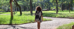 Estudante vista de costas carregando mochila, caminhando na Praça da Paz