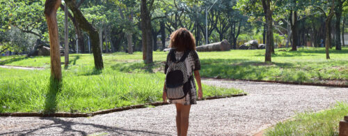 Estudante vista de costas carregando mochila, caminhando na Praça da Paz