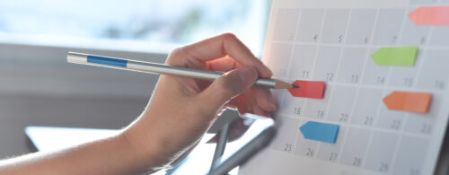 Mão marcando post-it em calendário