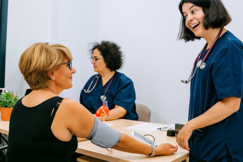 Enfermeira conversando com mulher enquanto ela faz exame para aferir sua pressão